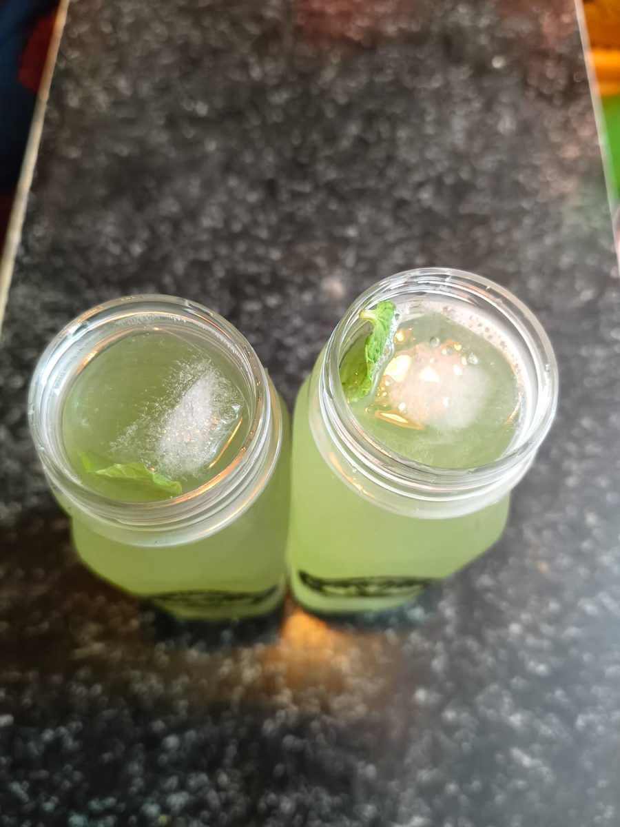 Top view of Irattai Panai Nizhal lemon mint juice bottles with ice and fresh mint garnish